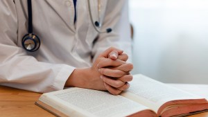 doctor praying with bible